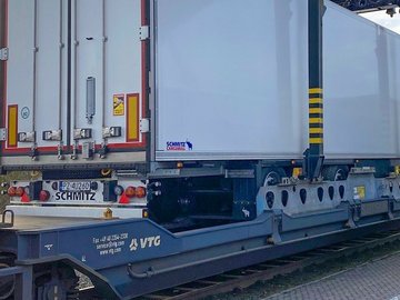 Weißer Trailer wird per Kran auf Waggon gehoben