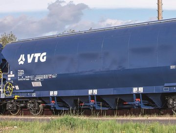 Blauer Hopper-Wagen mit weißem VTG-Logo vor grünem Hintergrund.