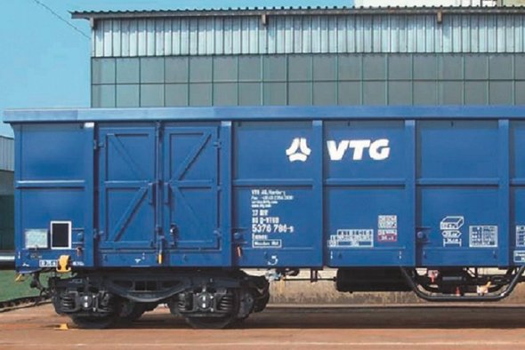 Blauer VTG-Boxwagen vor grauem Gebäude.