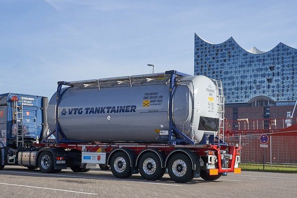 Grauer VTG-Tankcontainer auf einem blauem LKW vor der Elbphilarmonie in Hamburg.