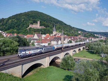 VTG-Ganzzug auf Schienenbrücke mit Häusern im Hintergrund