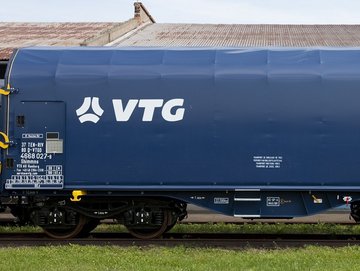 Blauer Flachwagen mit weißen VTG-Logo auf einer Schiene.
