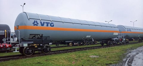 Grauer Flüssiggas-Kesselwagen mit orangem Streifen und blauem VTG-Logo.