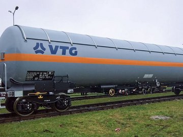 Grauer Flüssiggas-Kesselwagen mit orangem Streifen und blauem VTG-Logo.