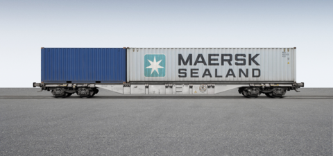 Grauer Containerwagen mit einem kleinen blauen Container und einem großen grauen Container darauf.