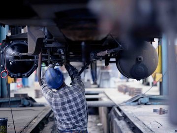 Mitarbeiter im Werk arbeitet unter einem Waggon in Grube 