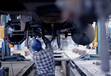 Mitarbeiter im Werk arbeitet unter einem Waggon in Grube 