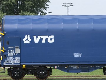 Blauer Flachwagen mit weißen VTG-Logo auf einer Schiene.