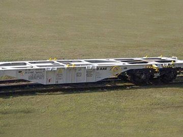 Grauer Containerwagen auf grünem Untergrund.